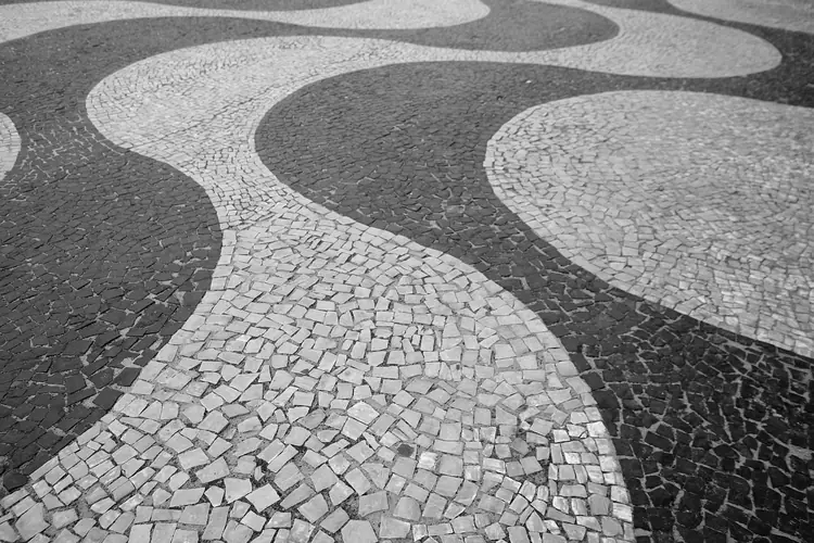 Close do calçadão de Copacabana, com as ondas de pedra portuguesa preta e branca.