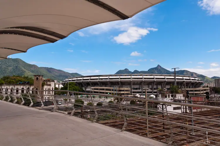 O Maracanã visto da plataforma da estação de trem, com os morros ao fundo.