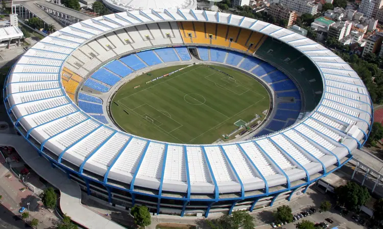 O Maracanã visto do alto a prumo, com o anel branco da cobertura, as cadeiras azuis e o gramado.